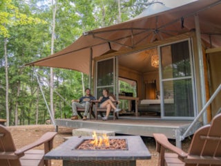 Two people sitting on a glamping tent porch in Maine at Point Sebago Resort.