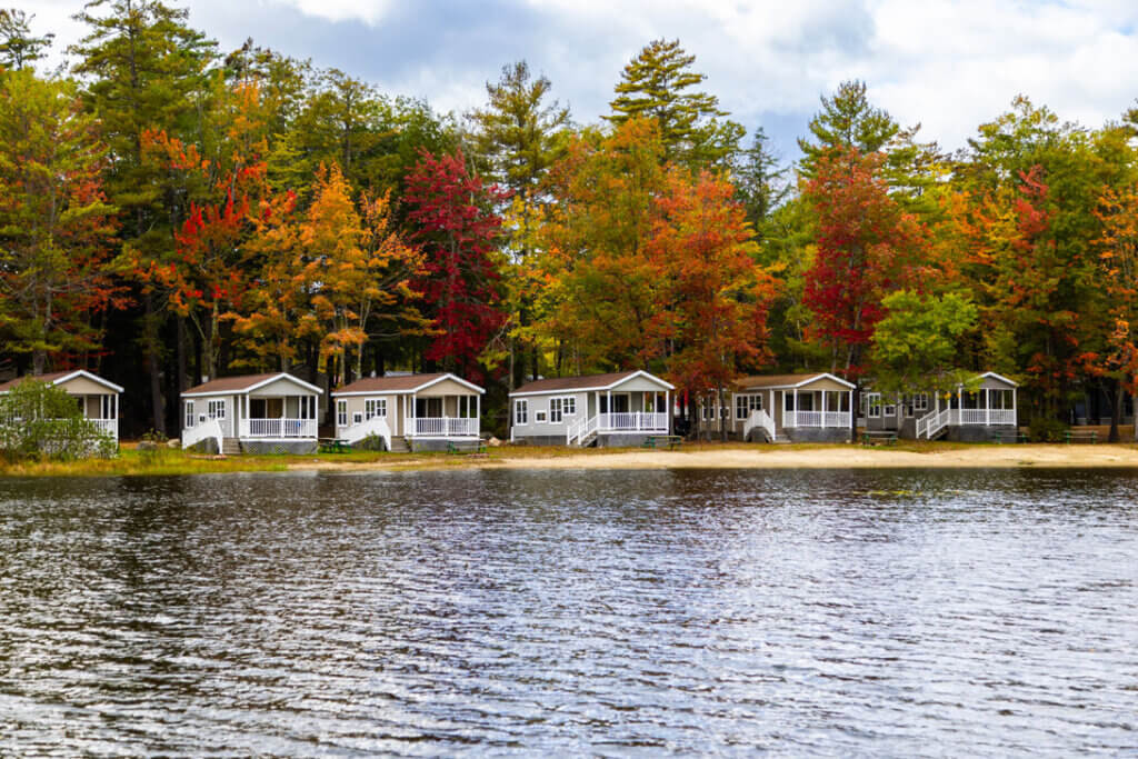Lagoon facing cabins at Point Sebago Resort in Maine. There are trees changing fall colors in the background.