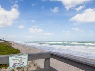 A beach with green grass and houses on the left