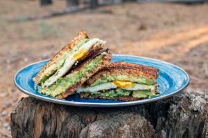 Breakfast sandwich on blue plate with avocado and egg