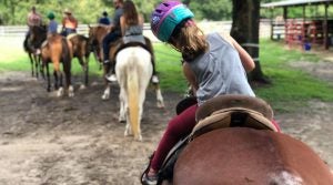 People on horseback, riding down a trail