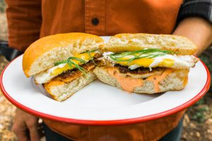 Breakfast sandwich on white plate with cheese and egg