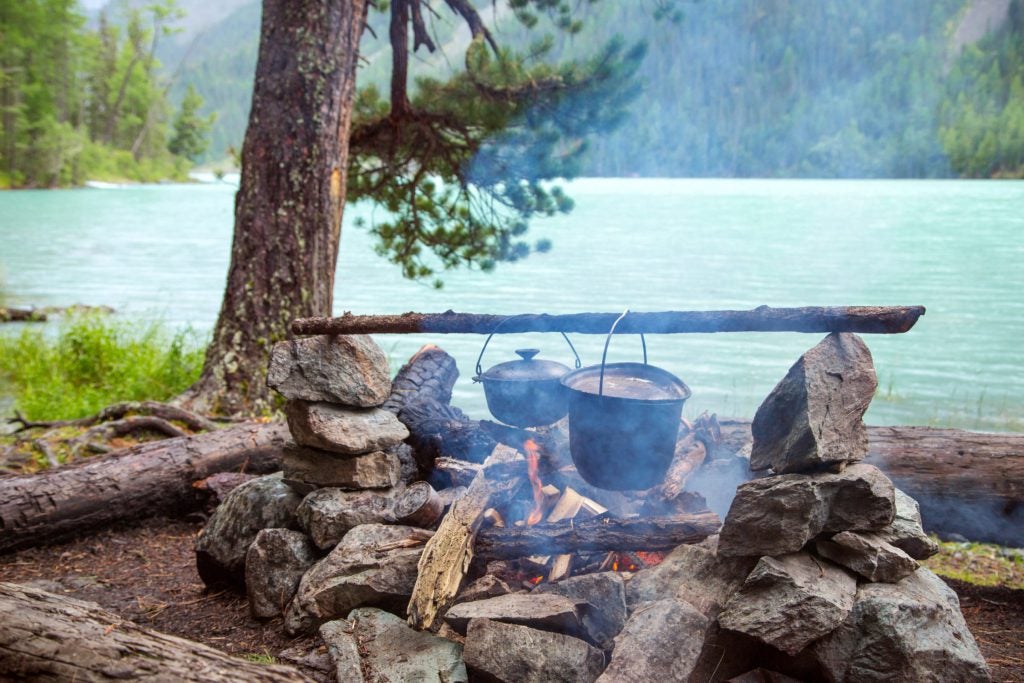 Pots hanging on a branch over a campfire