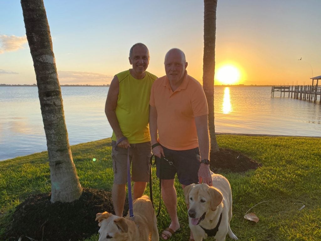 Two residents holding their dogs on leash at sunset with the Indian River in the background