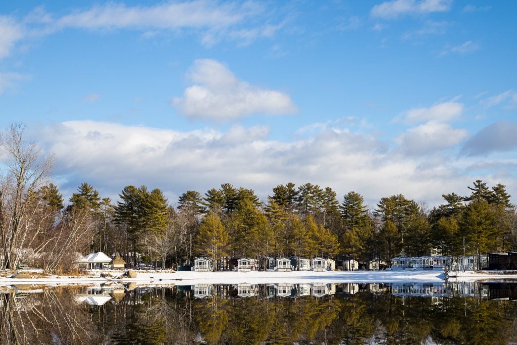 Houses along a lake with snow and trees surrounding them