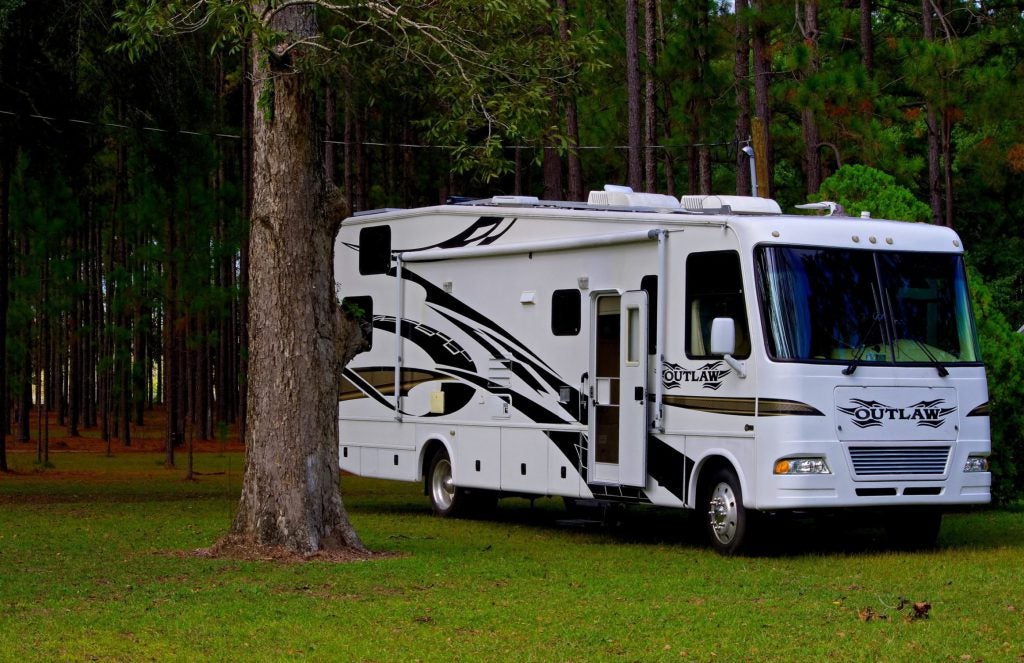 RV parked on grass surrounded by trees