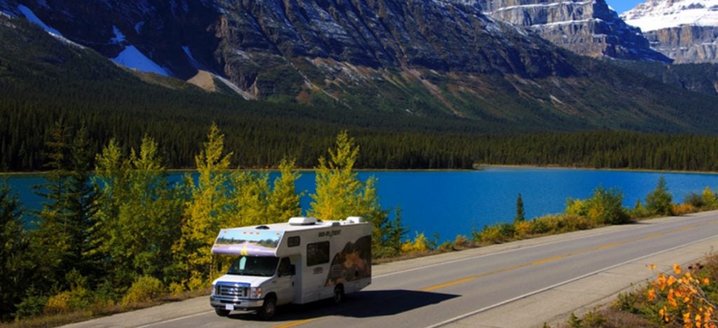 RV on road with mountain and river