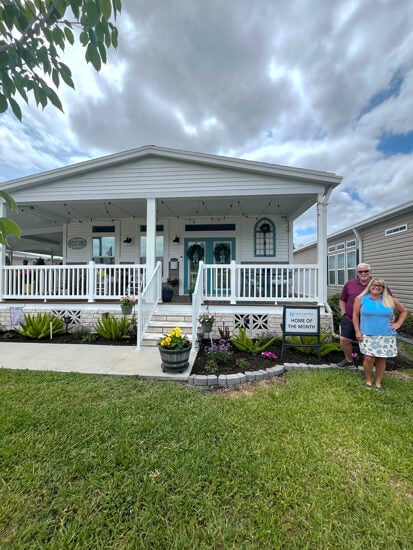 55+ Residents standing in yard after being awarded Home of the month at Cypress lakes Village in Lakeland, Florida.