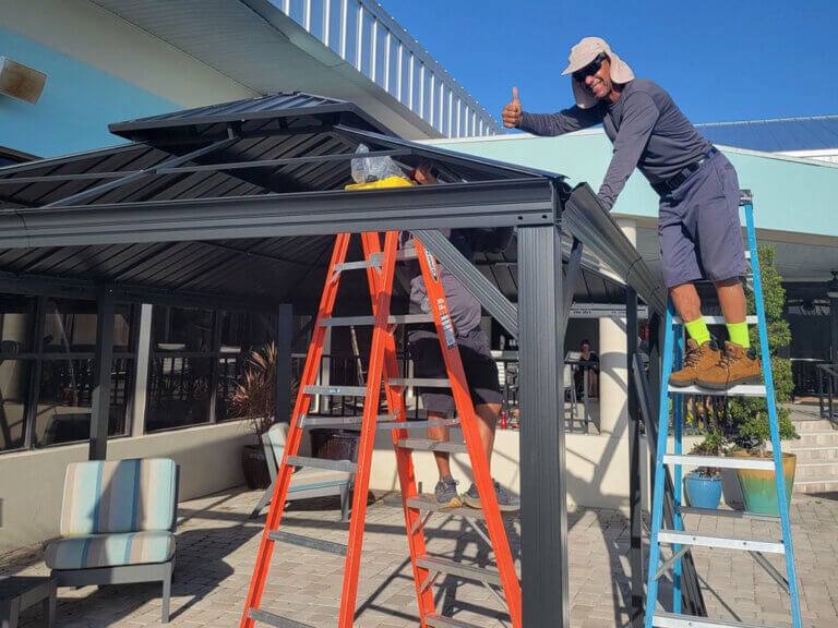 A man on a ladder installing the new swimming pool cabana at Camelot East Village in Sarasota, Florida.