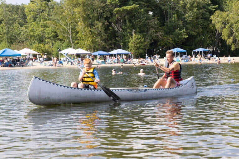 Father and son canoeing on Sebago Lake off the shores of Point Sebago Resort in Maine.