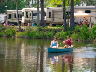 Couple canoeing in lake at Lake Jasper with RV's parked in the background
