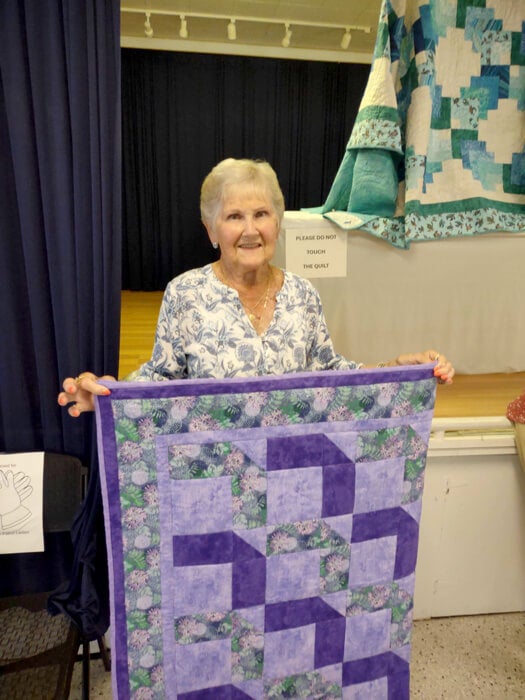 Guest at Holiday RV Park in Leesburg, FL holding a quilt at the Spring Quilt Show.