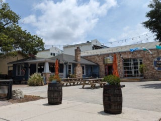 Two picnic tables with orange umbrellas on the outside of the Dunedin Brewery