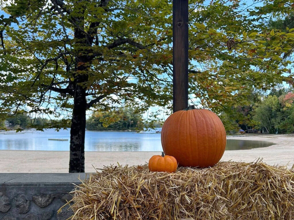 Two pumpkins with Sebago Lake on a hay bale with Sebago Lake in the background.