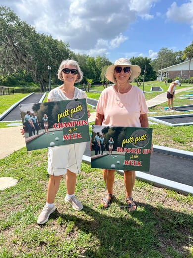 Guests holding a sign that says putt putt champion of the week at Holiday RV Park in Leesburg, Florida.