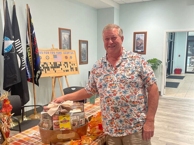 A man standing next to his raffle basket at Rolling Greens Village in Florida.