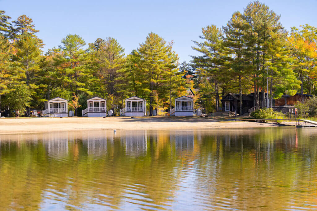 Cabins facing Sebago Lake with trees in the background starting to change color in October.
