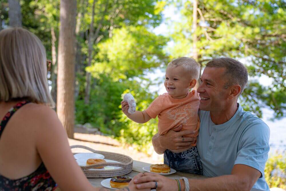 Family eating donuts outside the double decker cabins at Point Sebago Resort.