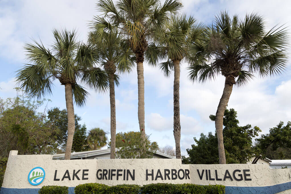 The entrances sign and five palm trees at Lake Griffin Harbor Village in Leesburg, Florida.