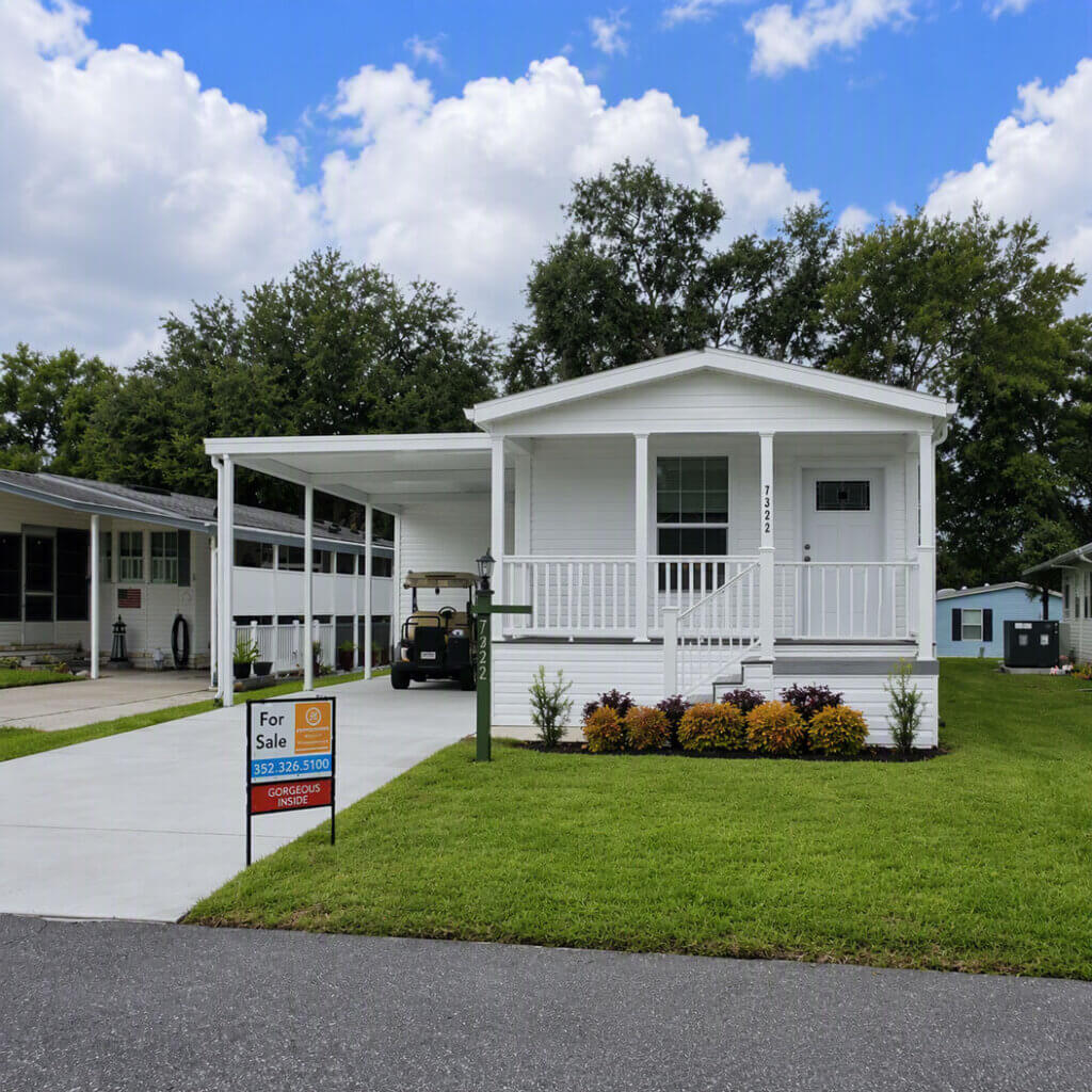 harbor-view-lake-grffin-home A white manufactured home with a manicured yard with a for sale sign at Lake Griffin Harbor Village in Leesburg, Florida.