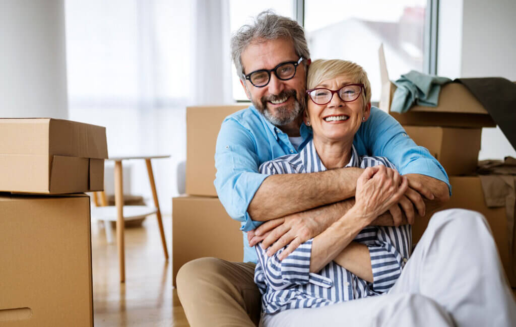Couples hugs next to their moving boxes