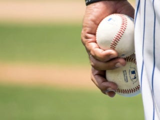 hand holding two baseballs
