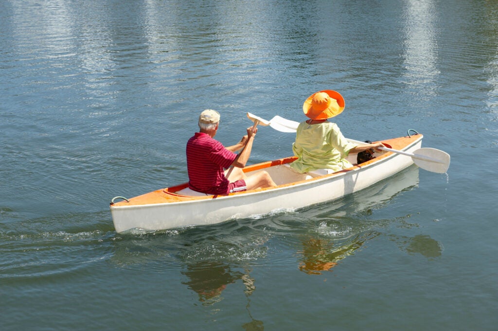 Older couple rowing canoe on lake