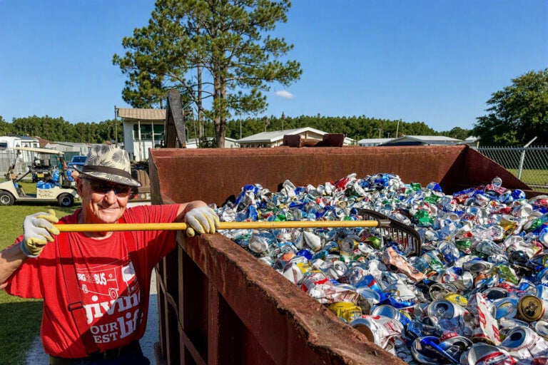 A man filling a dumpster with cans during Cypress Lakes Village recycling day.