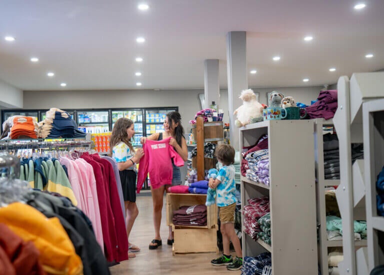 Mother, daughter, and son in the General Store at Point Sebago Resort in Casco, Maine looking at t-shirts.