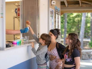 Mom and two kids getting a cone from the Ice Cream bar at Point Sebago