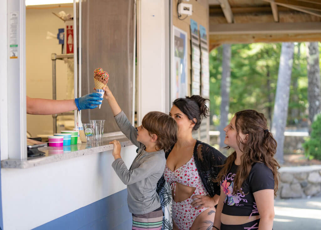 Mom and two kids getting a cone from the Ice Cream bar at Point Sebago