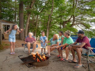 Family of seven around the campfire outside a cabin at Point Sebago Resort.