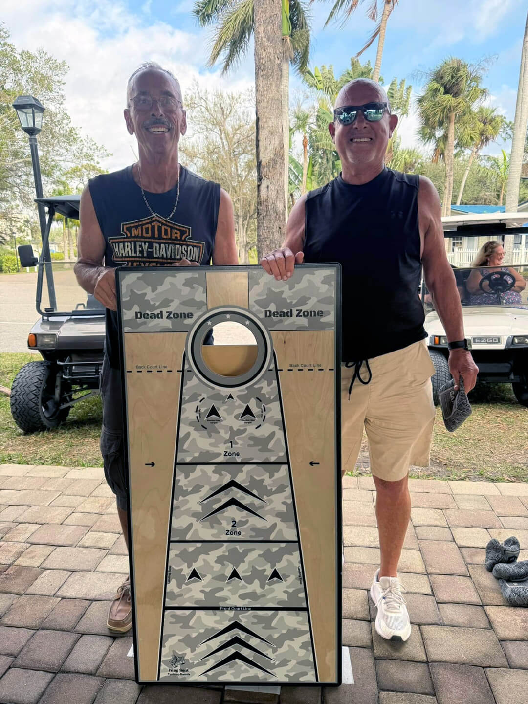 two guests holding up a cornhole board
