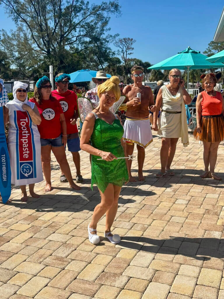 Guest at Blueway RV is shown in a Tinkerbell costume surrounded by other guests in different costumes at a themed pool party