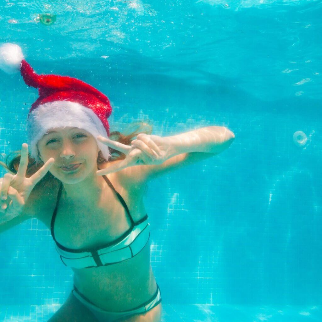 girl in swimming pool with Santa hat on