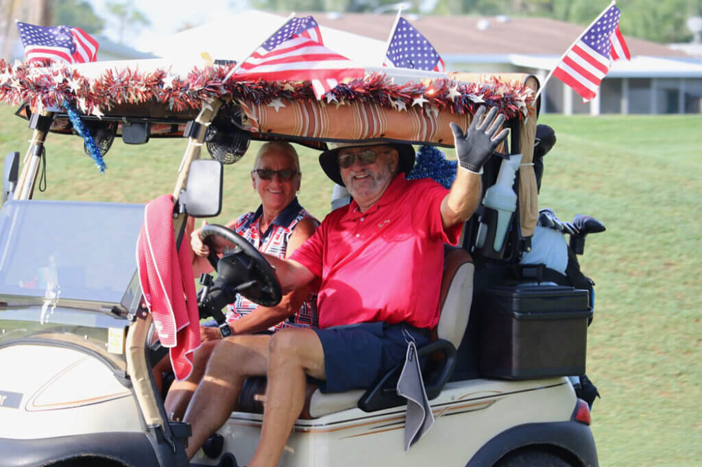 Couple riding in a golf cart decorated for July 4th in Lakeland, Florida at the Big Cypress Golf Club