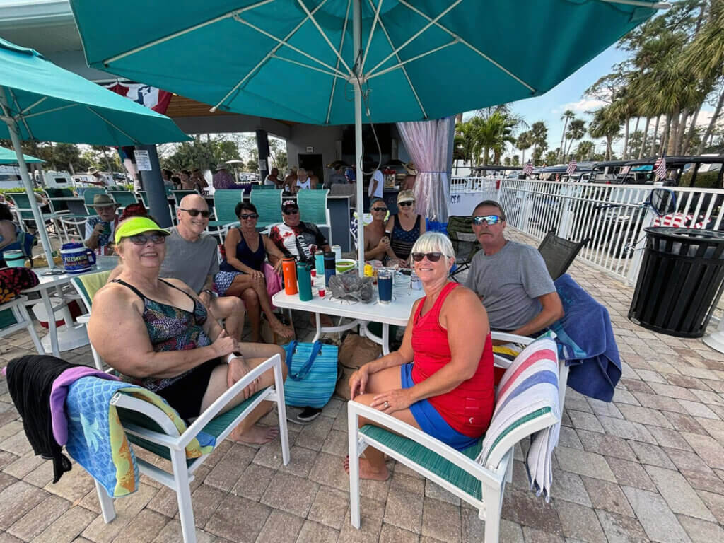 Guests at Blueway RV gather around a table on the pool deck to enjoy time with friends