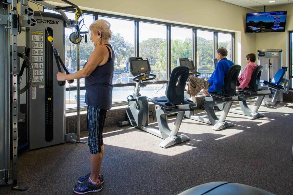 4 people using fitness machines in fitness center at Camelot Lakes Village.