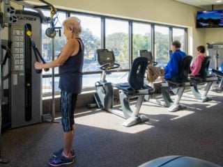 4 people using fitness machines in fitness center at Camelot Lakes Village.