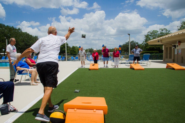 residents playing cornhole at camelot lakes village