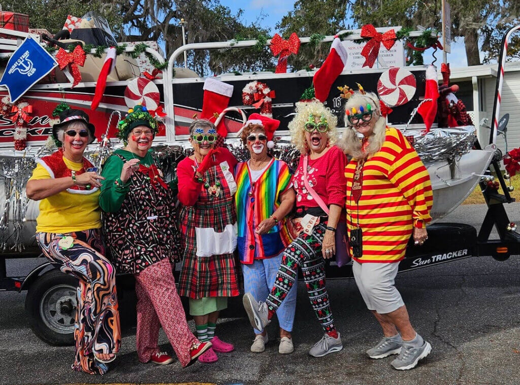 members of clown club in costume in front of a decorated boat at Christmas parade