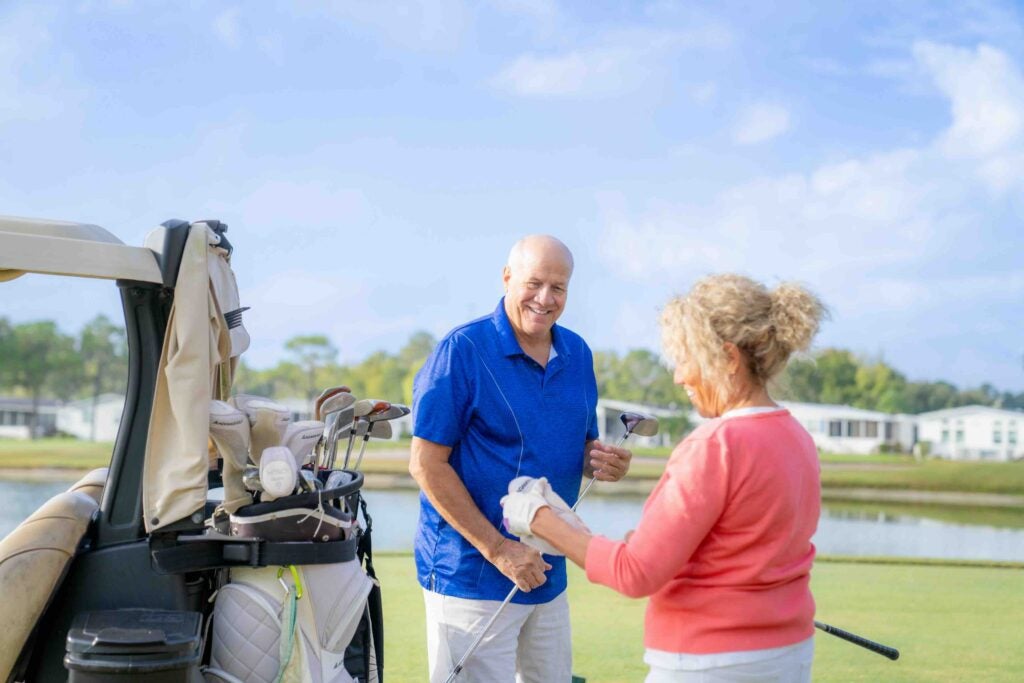 Camelot East Village - couple with golf club and cart