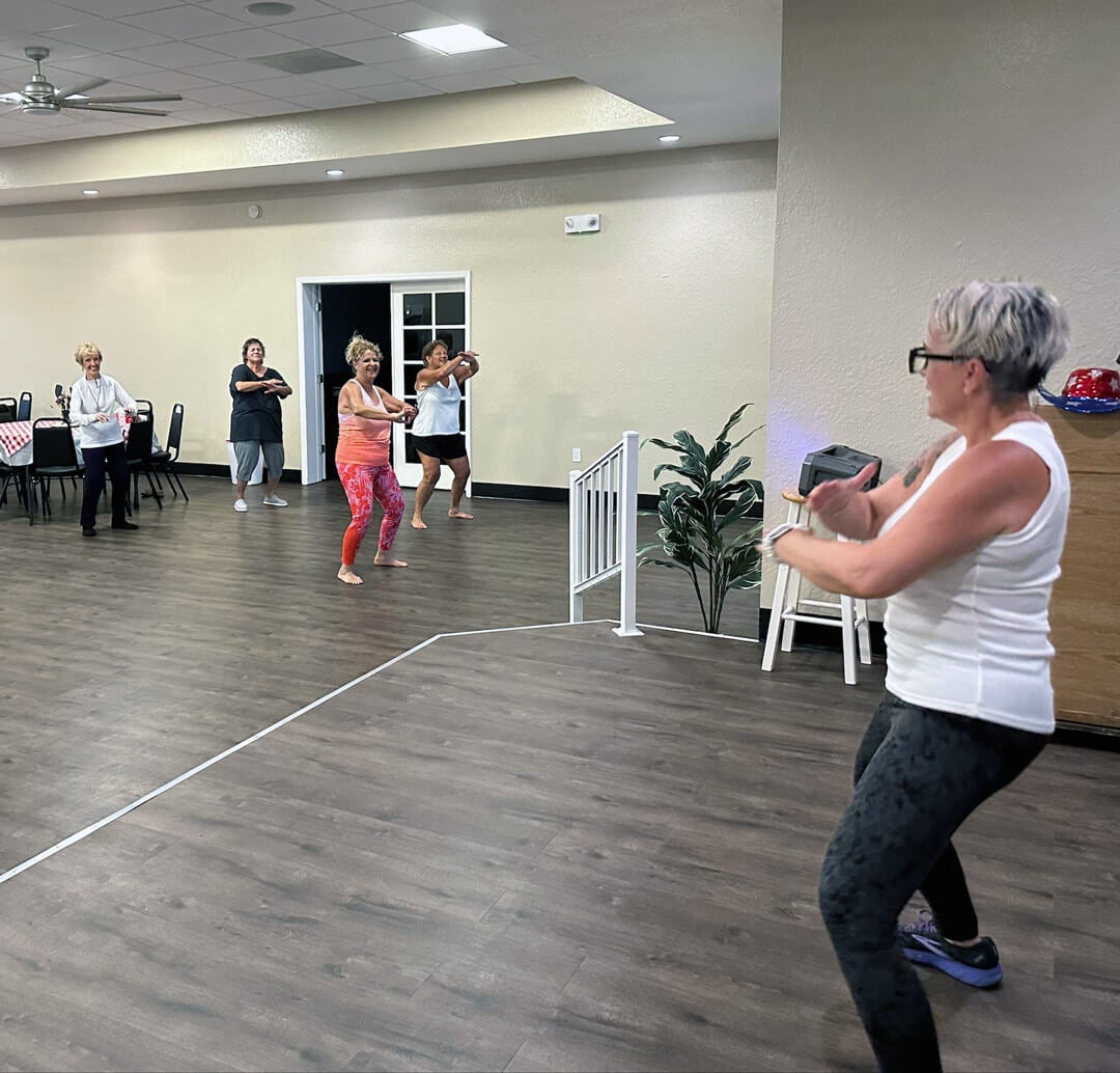 Dance fitness instructor leading residents in guided zumba workout in the clubhouse