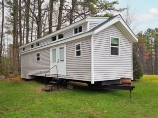 Off white Point Sebago Resort cabin with a double doors available at the model home center. Shown is an Elevation Park Model Series 5.