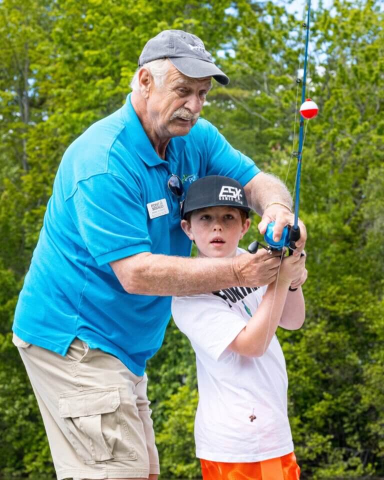Ranger Rick teaching a boy how to fish at Point Sebago Resort in Maine.