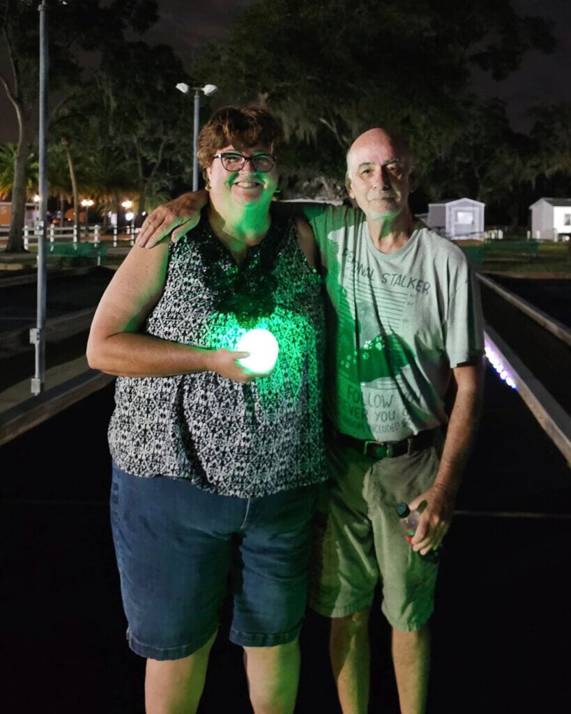 2 guests at Holiday RV Park hold Glow in the Dark Bocce balls from lifestyle activity.