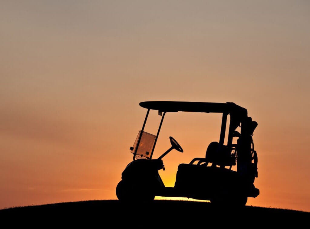 Beauty shot of golf cart on a hill with sun setting in the background.