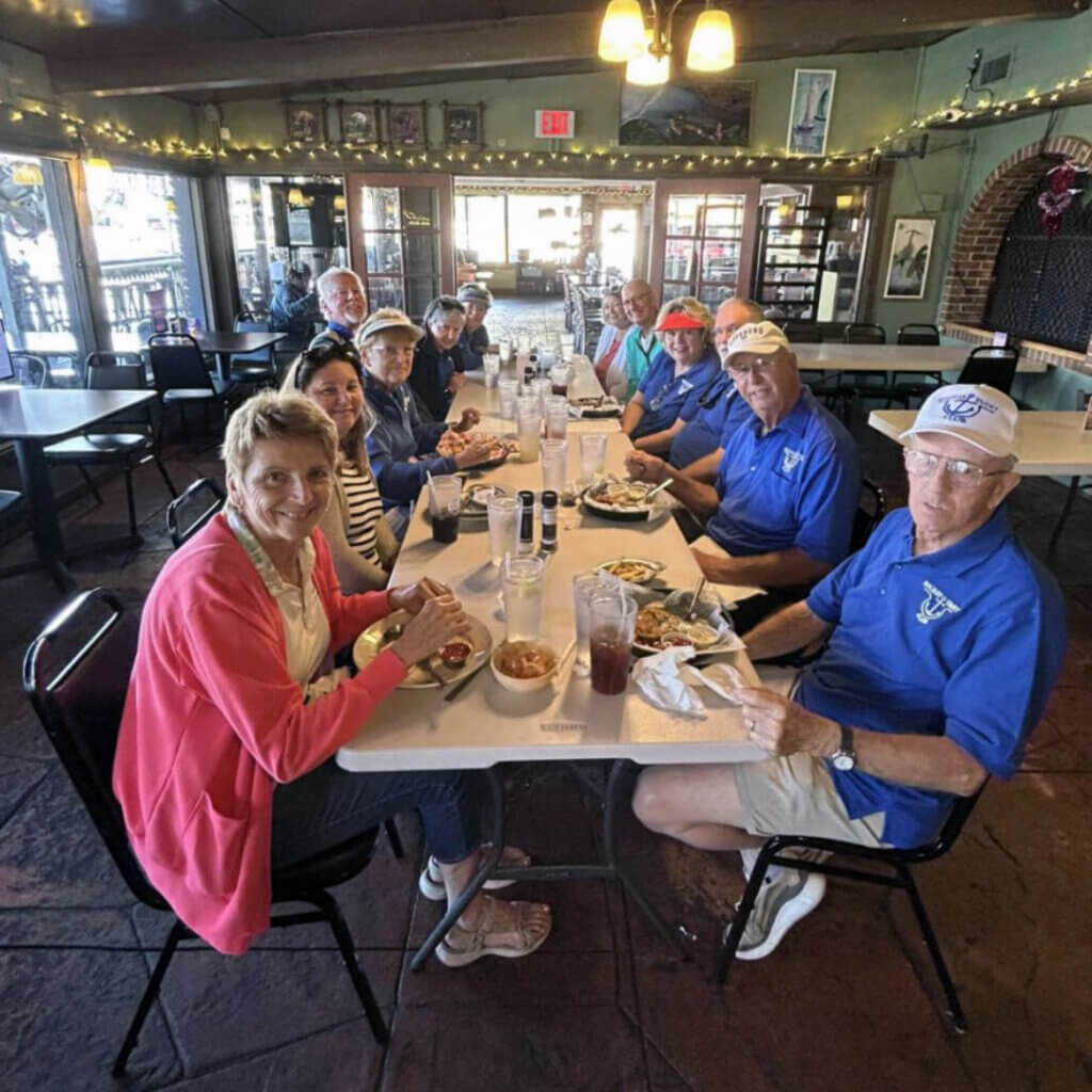 members of the yacht club sitting around the table having a lunch meeting
