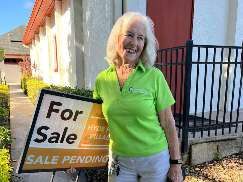Woman holding a "sale pending" sign a Hyde Park Village in Florida.