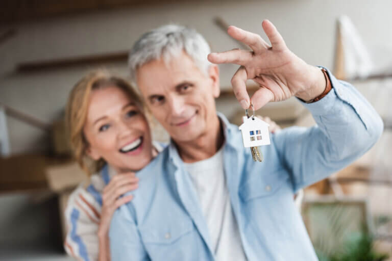 Happy senior couple holding keys from new nome during relocation
